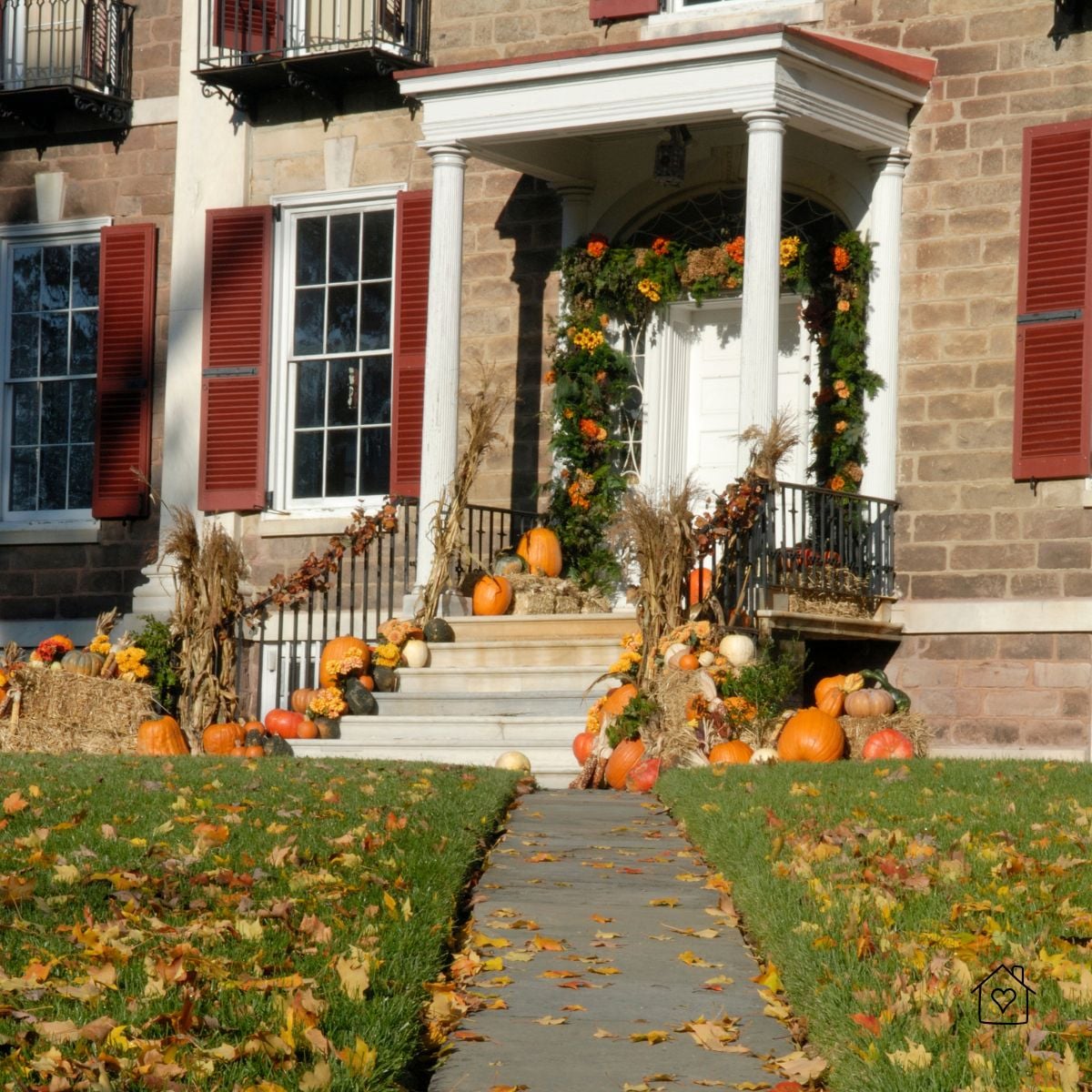 Front steps lined with pumpkins and autumn d&eacute;cor; leaves on path highlight the need for regular sweeping and care.