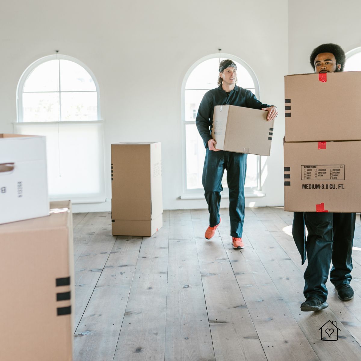 Professional movers carrying large boxes inside a house during a California move
