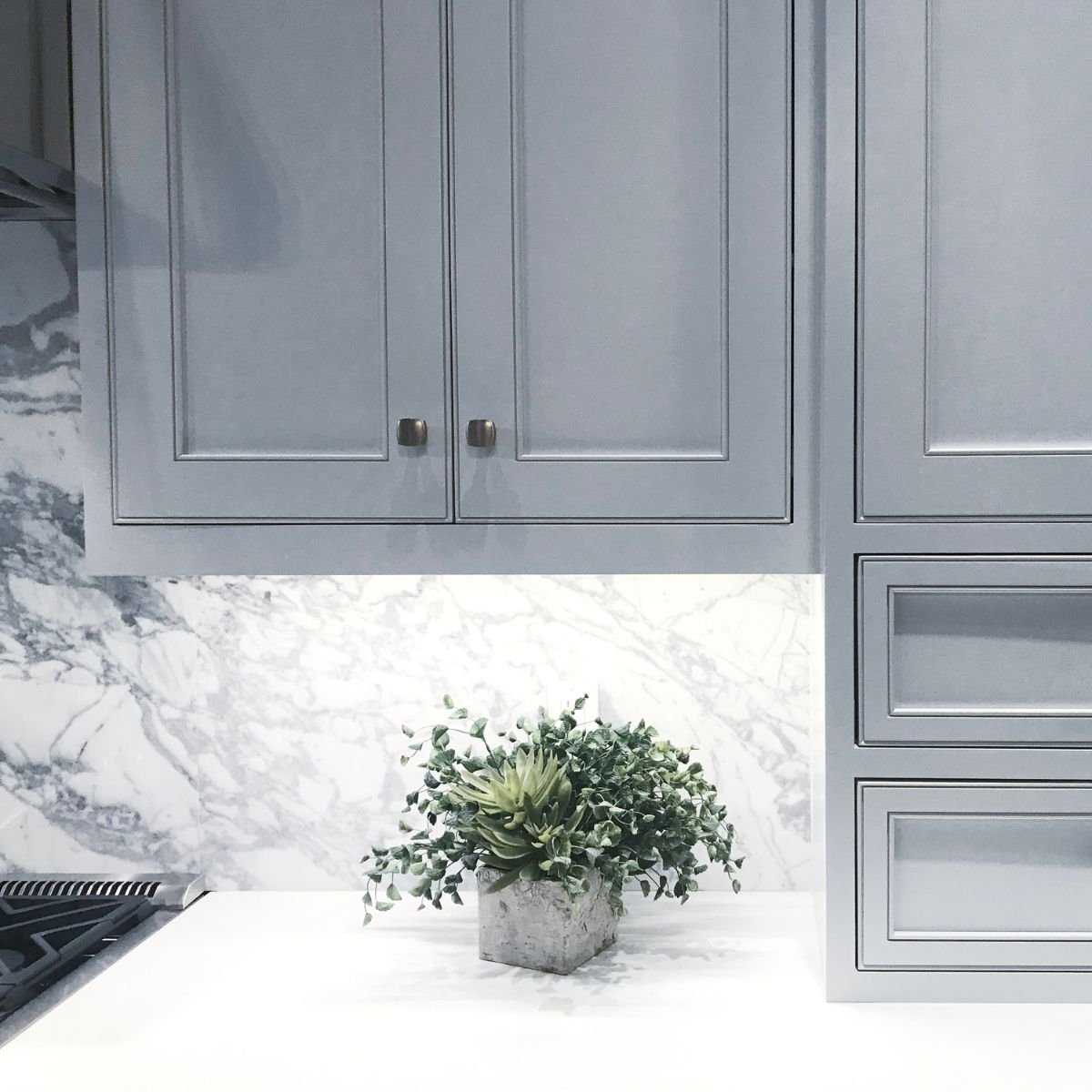 Spacious gray and white kitchen featuring glossy marble countertops, chrome fixtures, and bright pendant lighting.