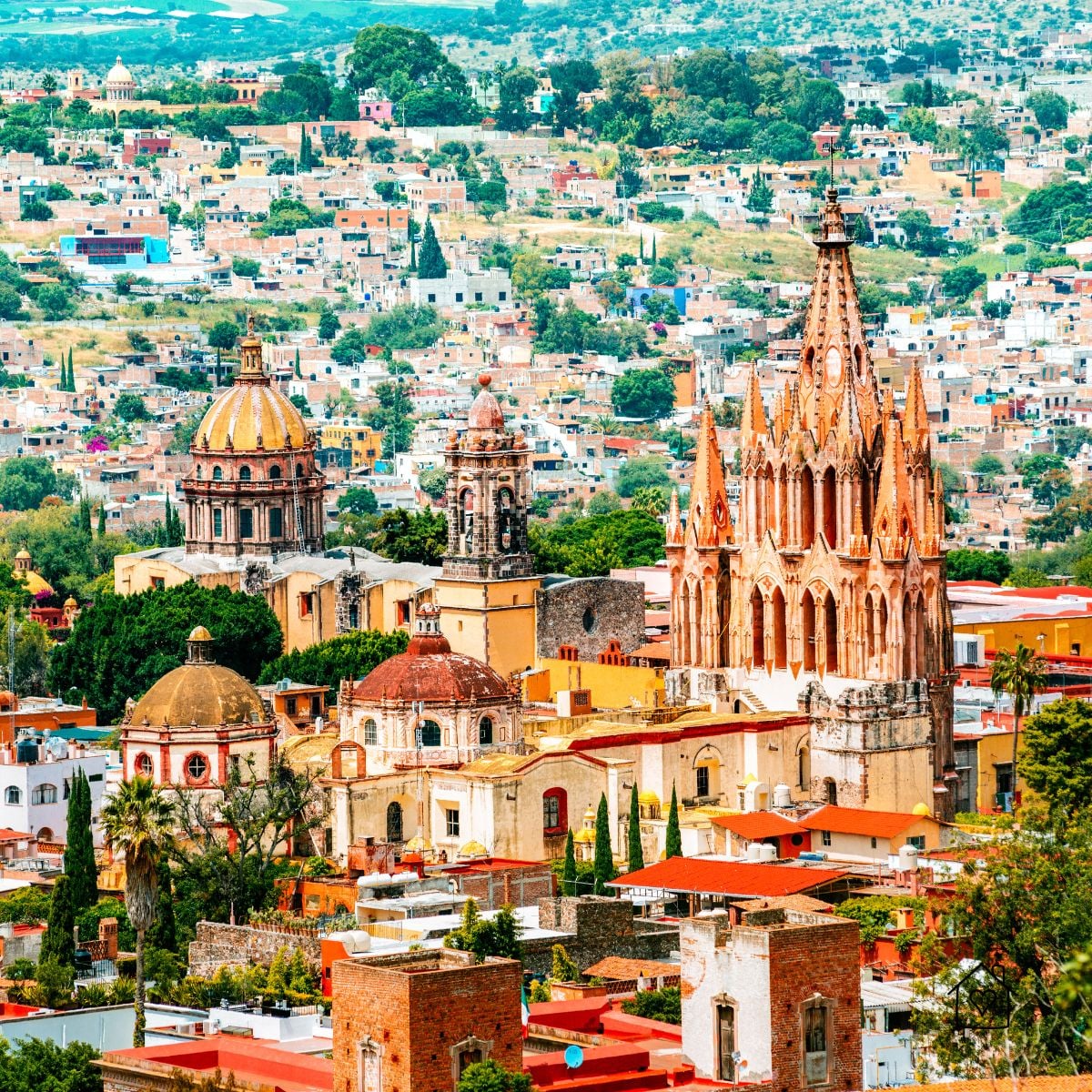 Colorful colonial rooftops with domes and the neo-Gothic Parroquia de San Miguel Arcángel in San Miguel de Allende, Mexico.