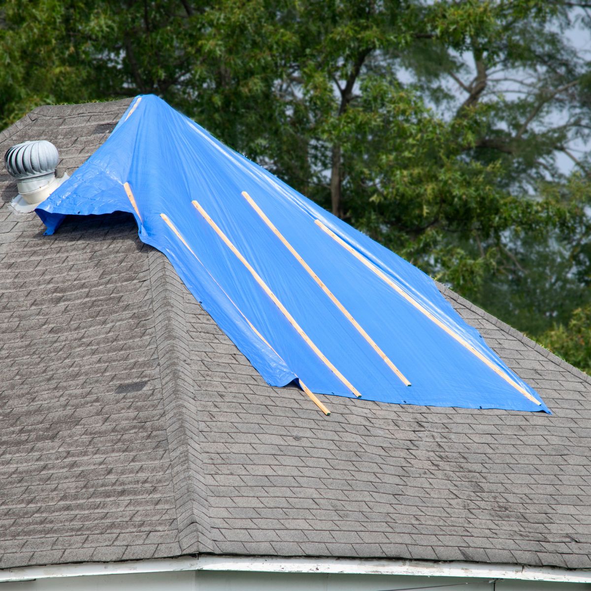 House roof covered with a blue tarp as a temporary fix to prevent water leaks after storm damage in Texas.