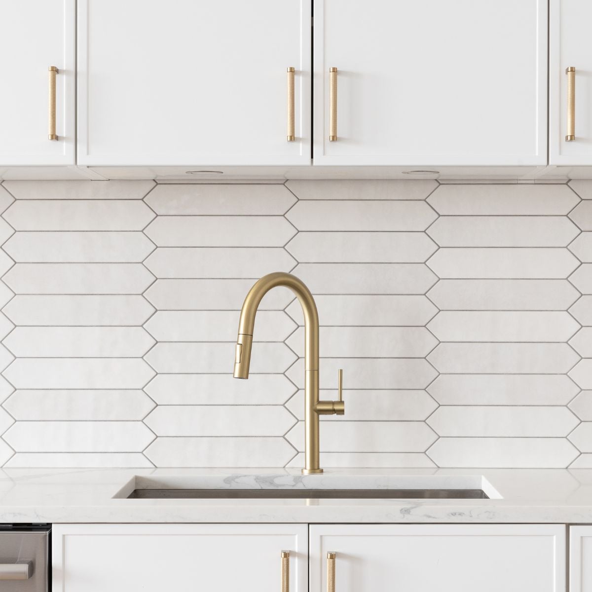 White kitchen cabinets with gold handles and a modern gold faucet, paired with a geometric white backsplash.