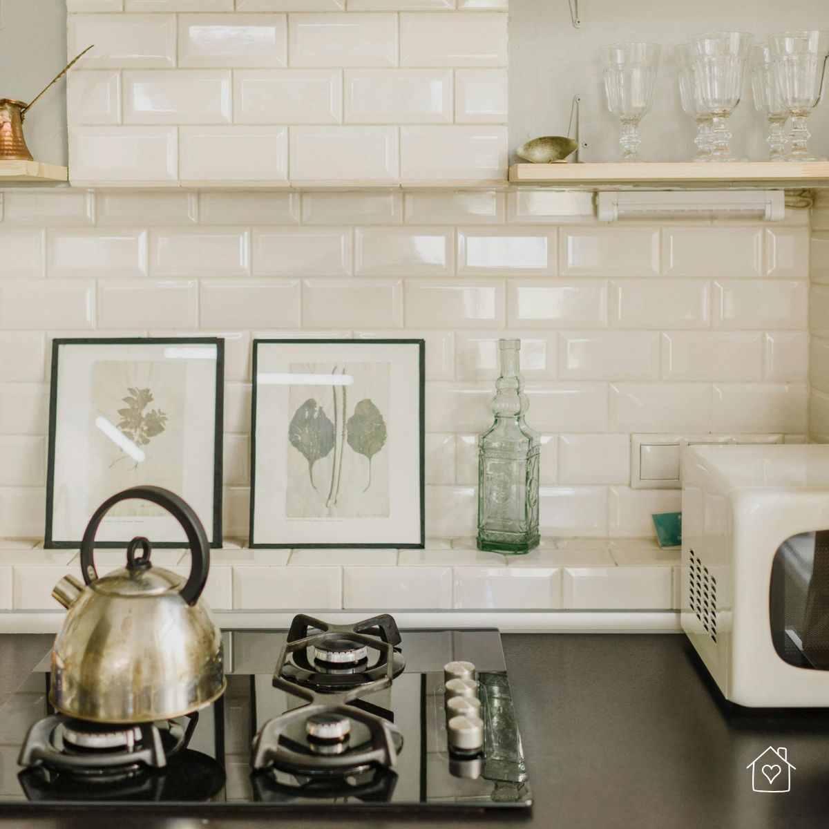 Clean white tile backsplash with stove, kettle, and neatly arranged kitchen décor.