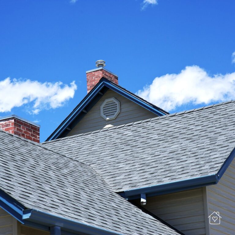 Gable roof with ridge cap, attic vent, and brick chimney against a bright blue sky.