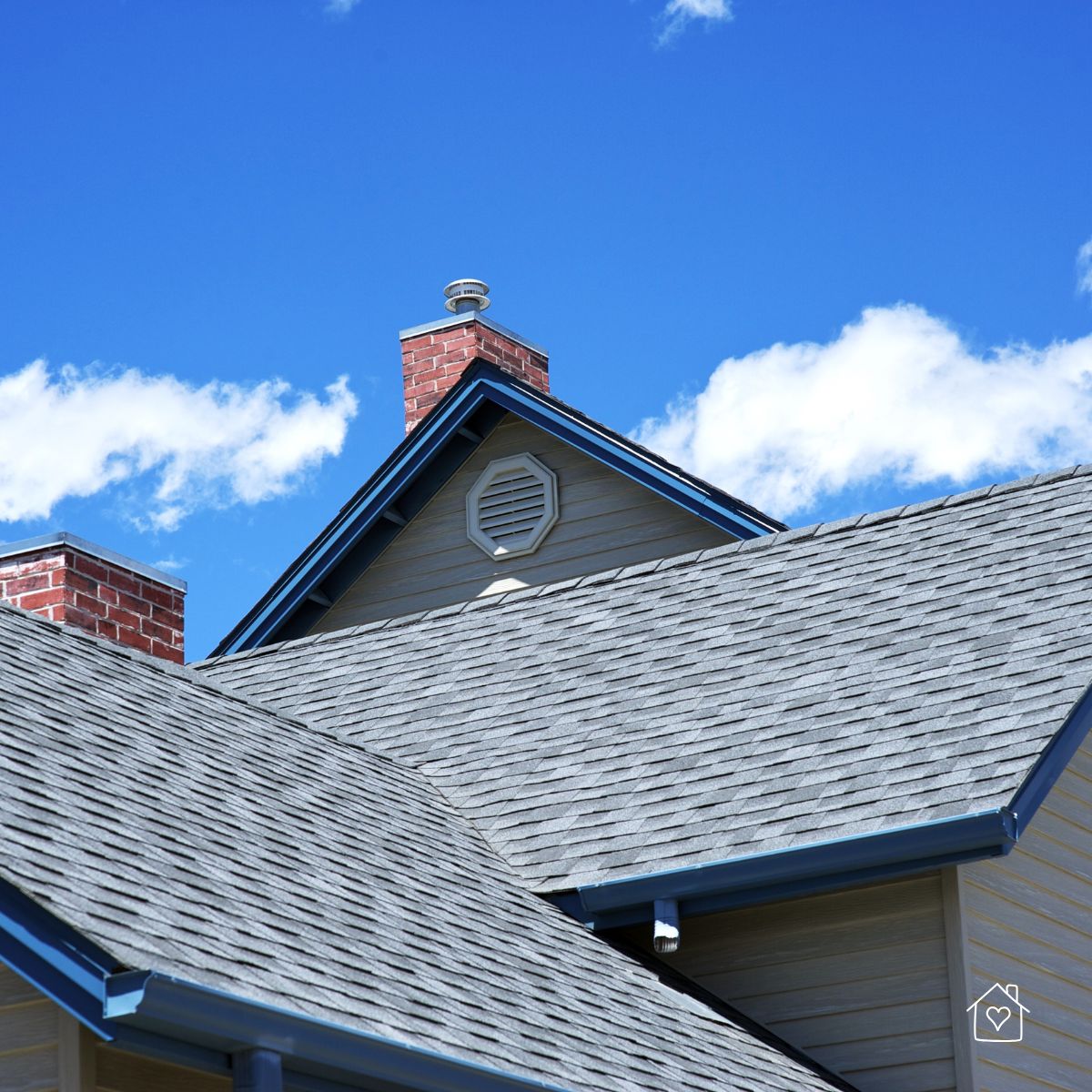 Gable roof with ridge cap, attic vent, and brick chimney against a bright blue sky.