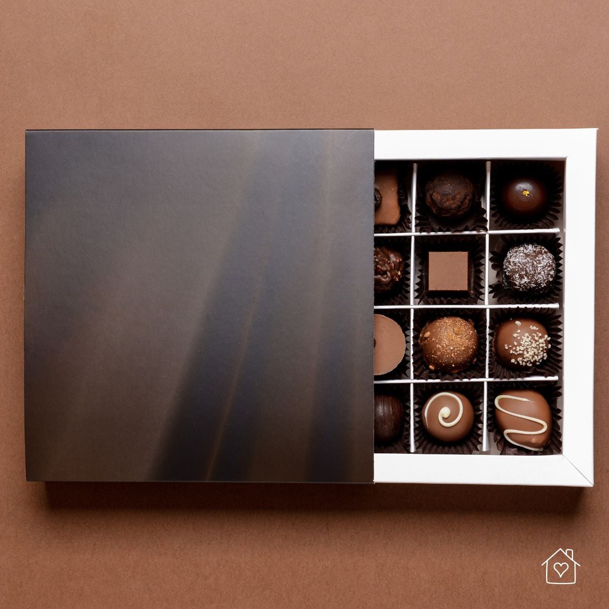 Top-down view of a partitioned box of luxury chocolates, partially covered by a sliding lid—illustrating proper storage and display.