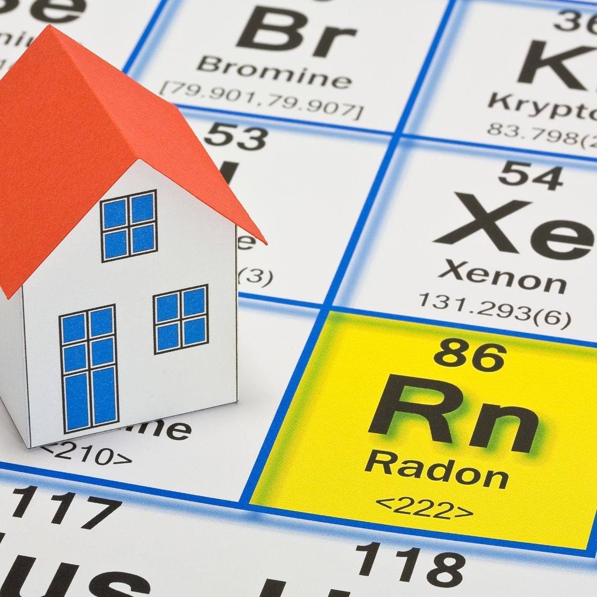 Paper house sitting on a periodic table with the radon (Rn) square highlighted, symbolizing indoor radon risk.