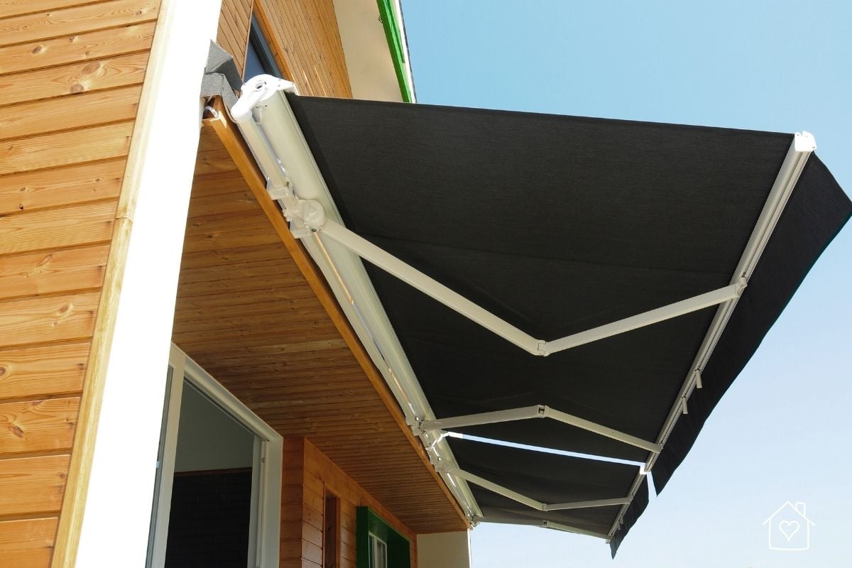 Black motorized retractable awning extended from a wood soffit over a patio