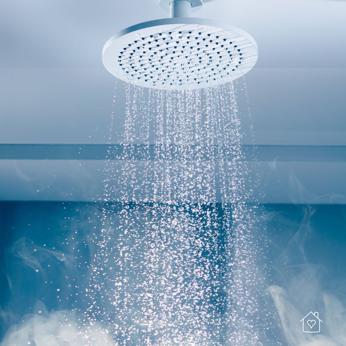 Close-up of a modern rainfall showerhead releasing hot water with visible steam filling the bathroom, illustrating a source of indoor humidity.