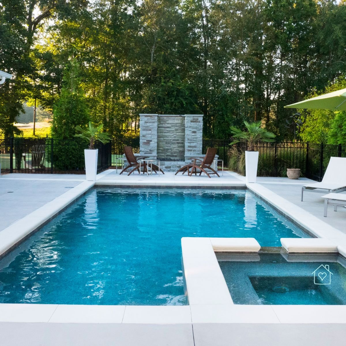 Modern backyard pool surrounded by lounge chairs and greenery, creating a serene outdoor retreat.