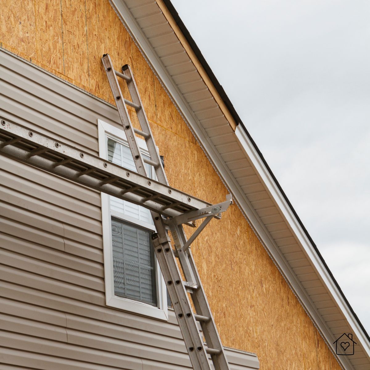 Contractor ladders against a New Jersey home with exposed OSB sheathing and vinyl siding in progress