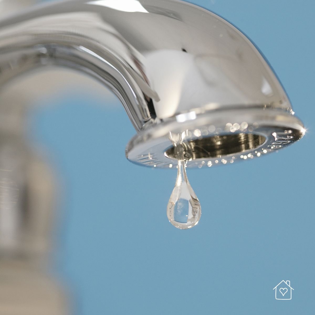 Close-up of a chrome faucet with a single droplet forming—an early sign of a leak that wastes water and raises bills.