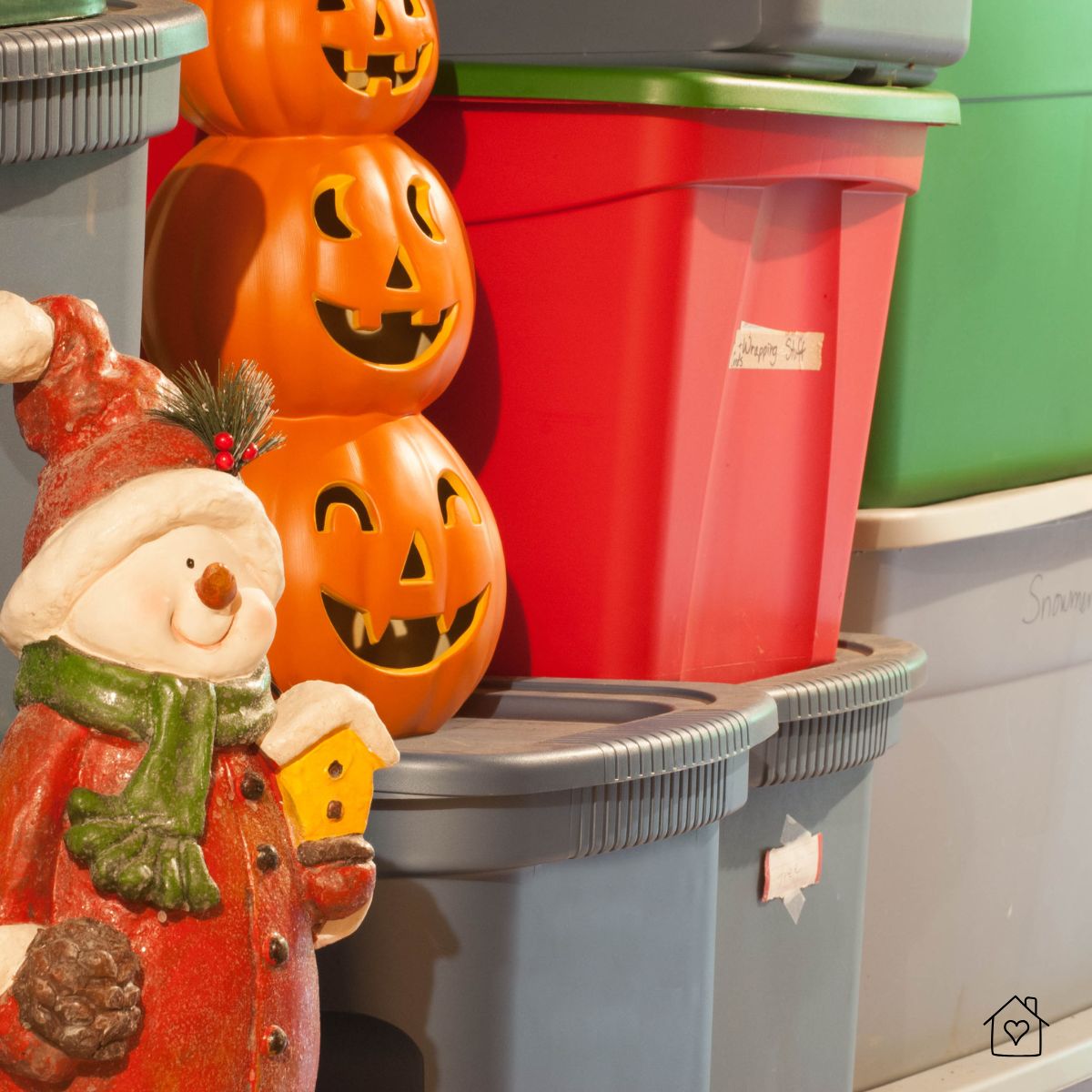 Labeled red and green storage totes with stacked jack-o’-lanterns and a snowman figurine, ready for outdoor shed storage.