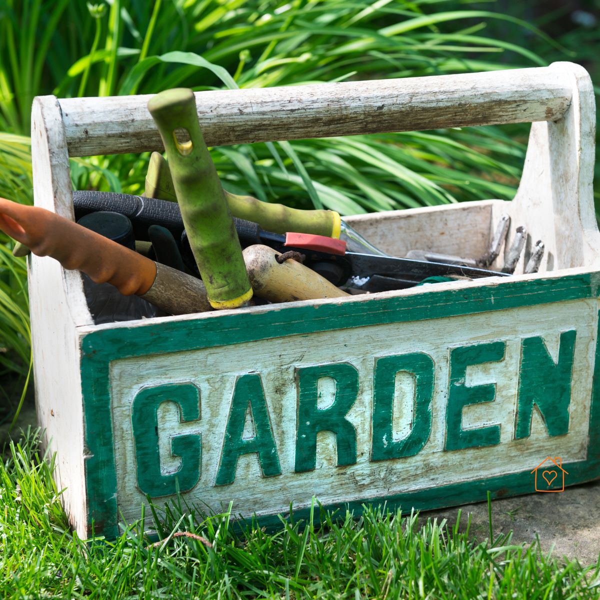 Wooden garden caddy filled with hand tools on lawn.