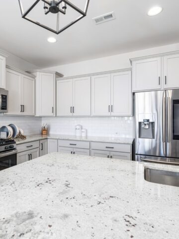 Bright Chicago kitchen featuring light granite countertops, white cabinetry, stainless steel appliances, and a clean, contemporary design aesthetic.