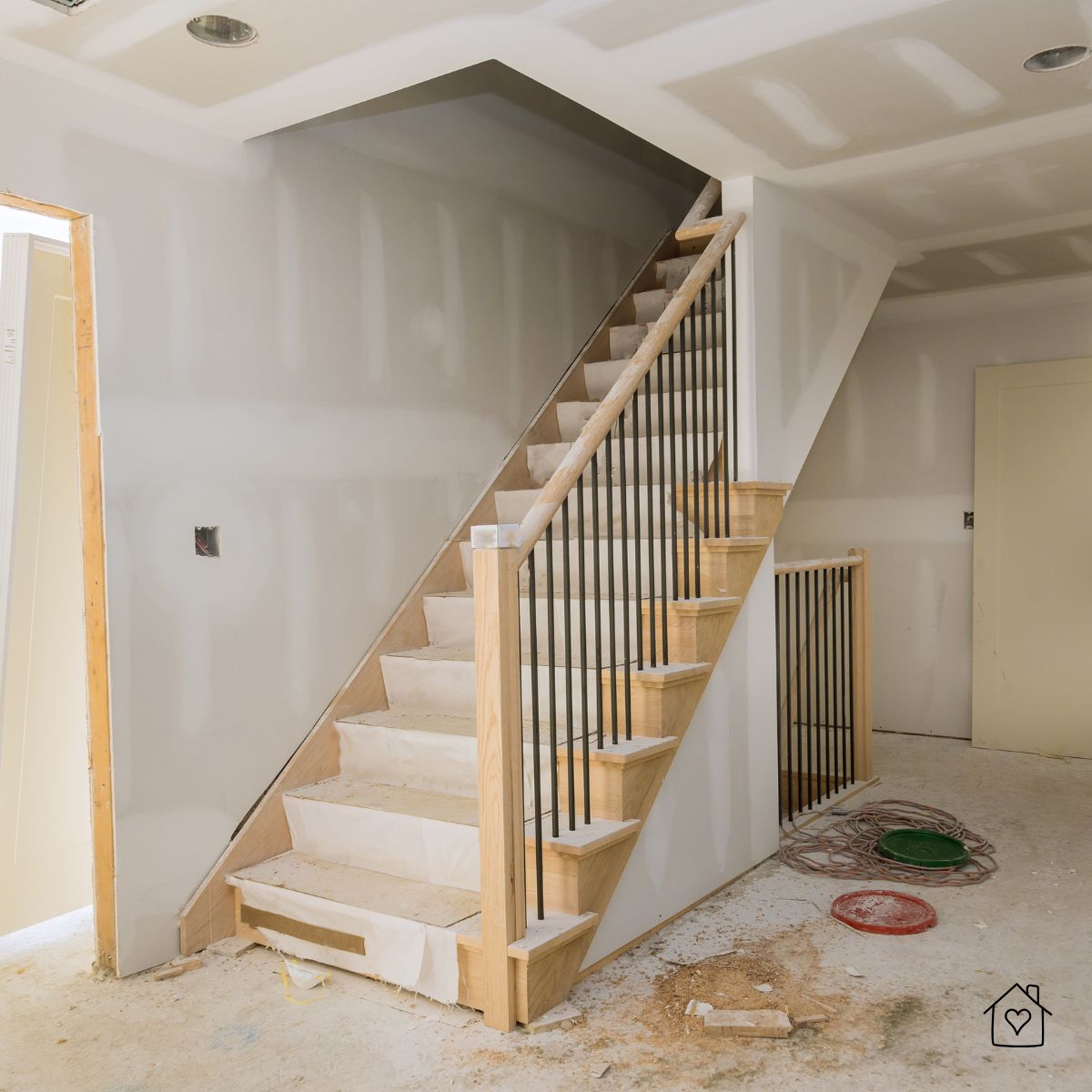 Partially finished wooden staircase with black railings in a Milwaukee home renovation, highlighting the early stages of carpentry work.