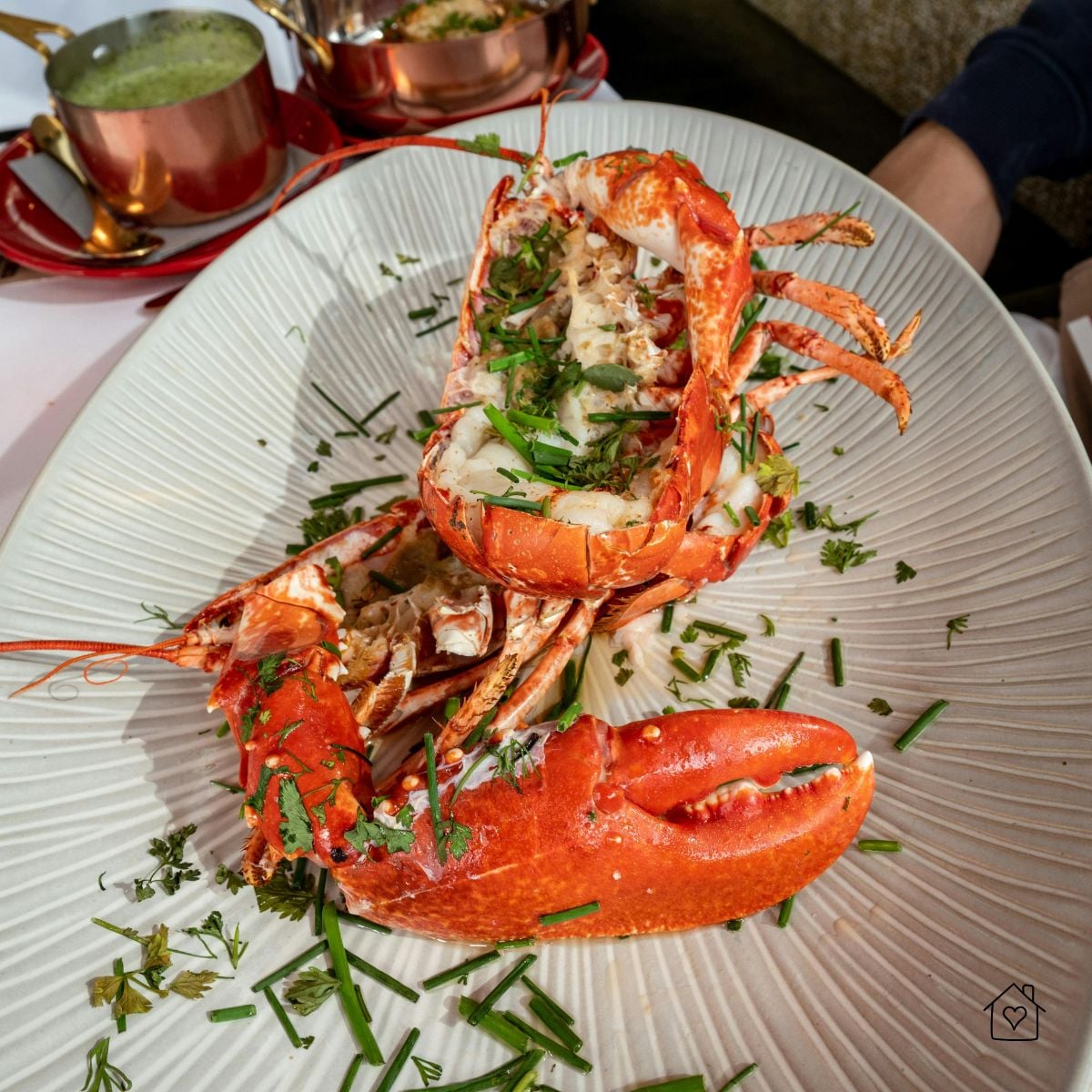 A halved lobster served on a plate, garnished with chopped herbs, ready to enjoy in a fine dining setting.