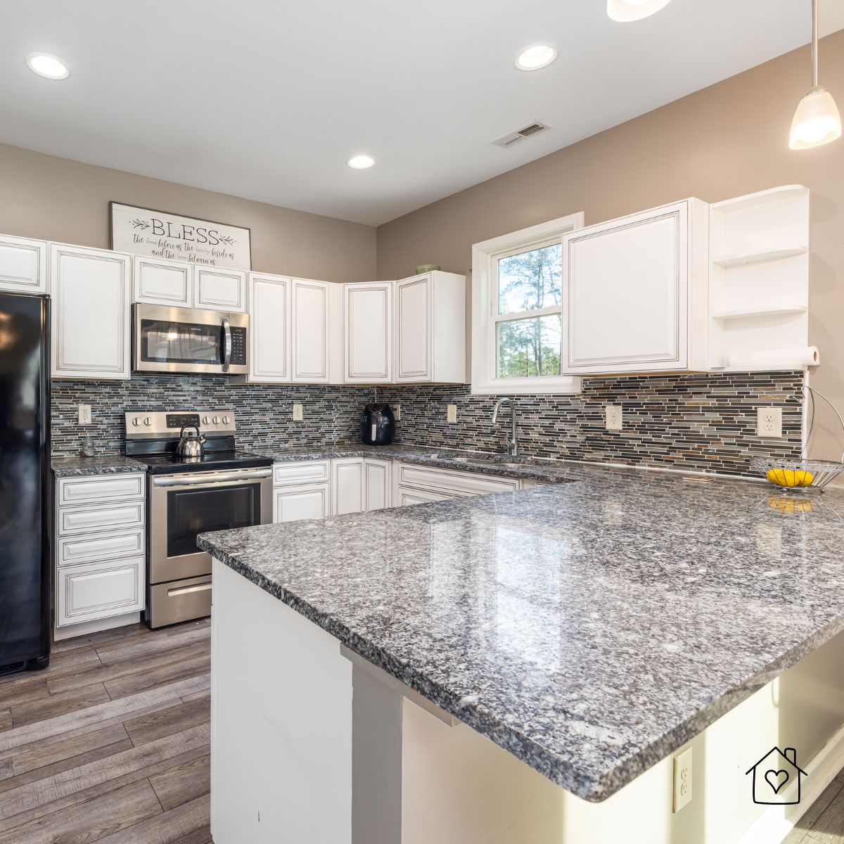 Modern kitchen in Chicago with polished gray granite countertops, white cabinets, stainless steel appliances, and a mosaic tile backsplash.