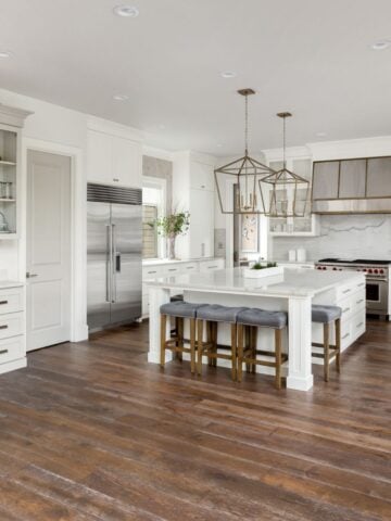 Bright kitchen with white cabinetry, pendant lighting, and dark-stained hardwood floors freshly refinished.