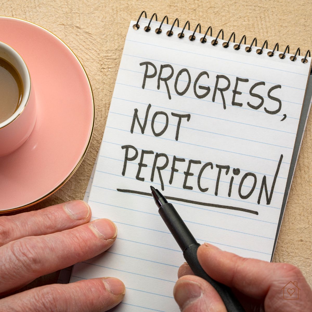 Handwriting on notebook reads “Progress, Not Perfection” beside coffee cup.