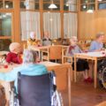 Group of senior residents sitting together in a nursing home dining room, illustrating community life and social interaction in long-term care facilities.
