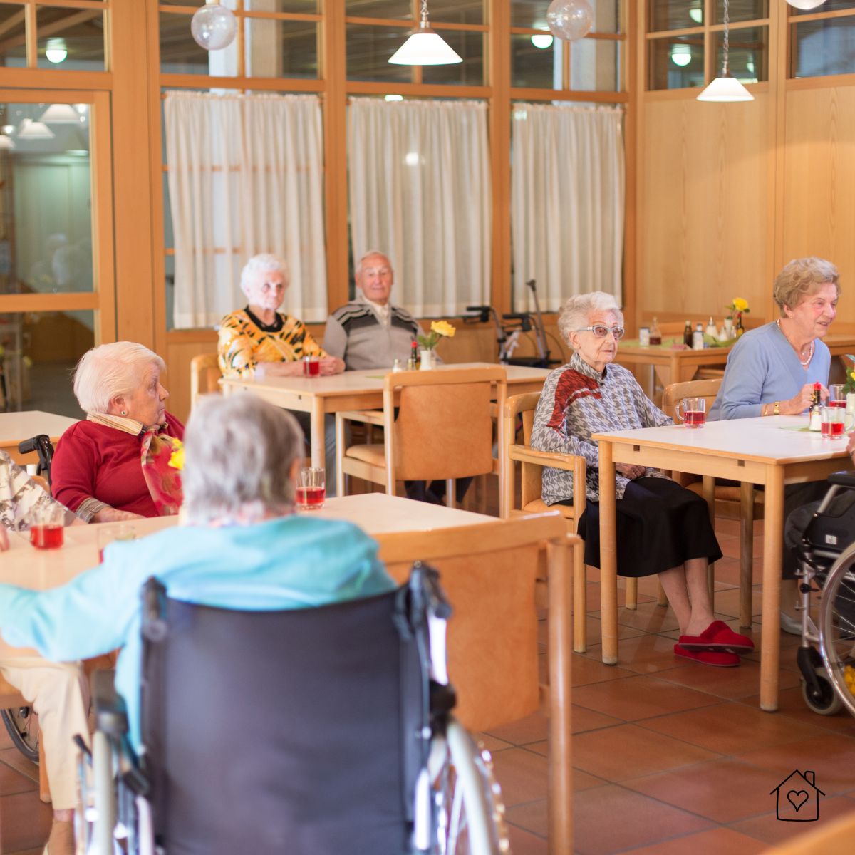 Group of senior residents sitting together in a nursing home dining room, illustrating community life and social interaction in long-term care facilities.