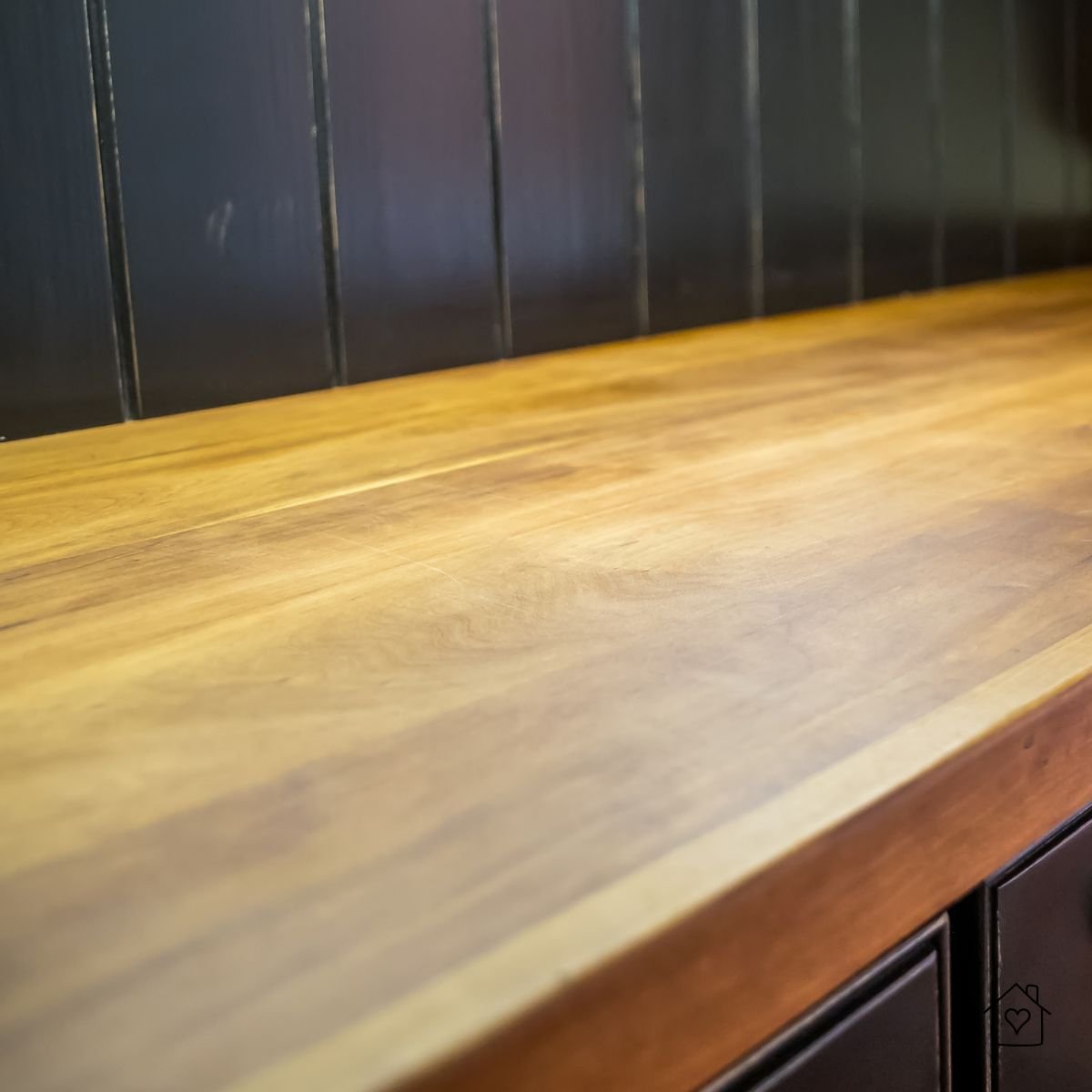 Oiled wood countertop against dark cabinetry, shallow depth of field.
