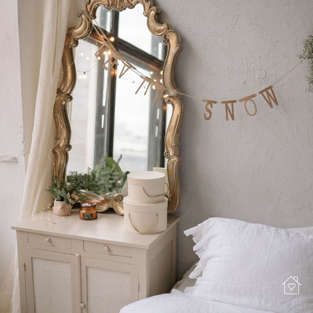 Cozy bedroom vignette with an ornate gold mirror above a small cabinet, showing how mirrors reflect window light to brighten darker corners.