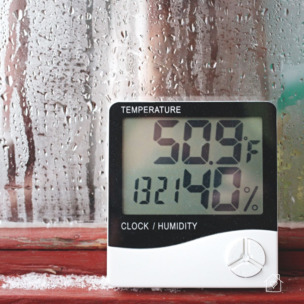 Digital temperature and humidity meter displaying high moisture readings against a fogged window background.