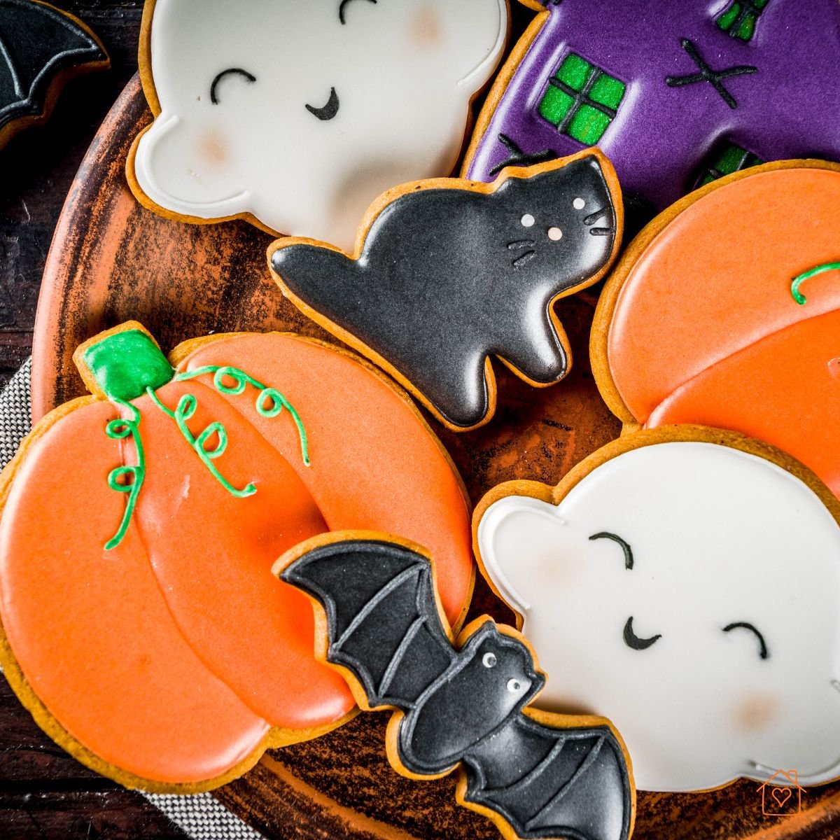 Decorated cookies shaped like pumpkins, bats, ghosts, and cats with colorful icing.