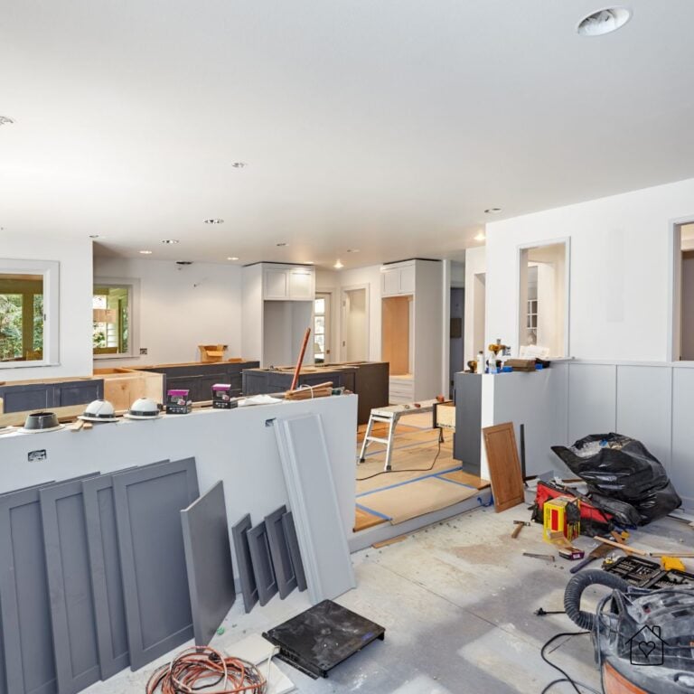 Large open-concept kitchen and living area in Milwaukee under renovation, with gray cabinetry, tools, and materials spread across the floor.