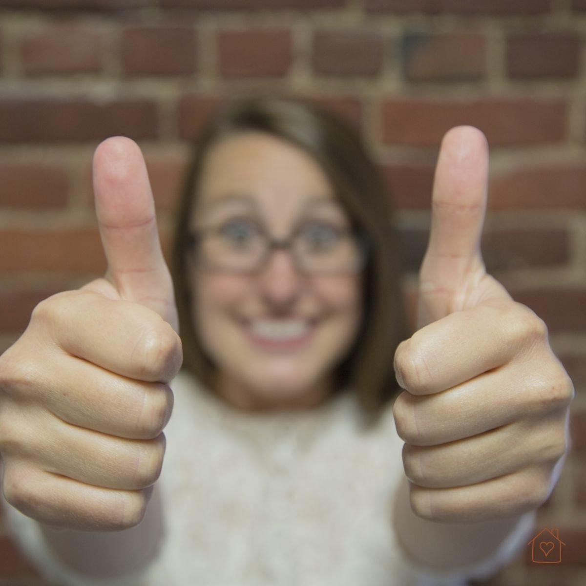 Smiling woman with two thumbs up, modeling positive self-approval.