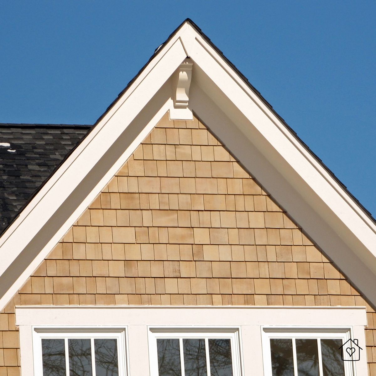 House gable clad in natural cedar shingles above white-trimmed windows