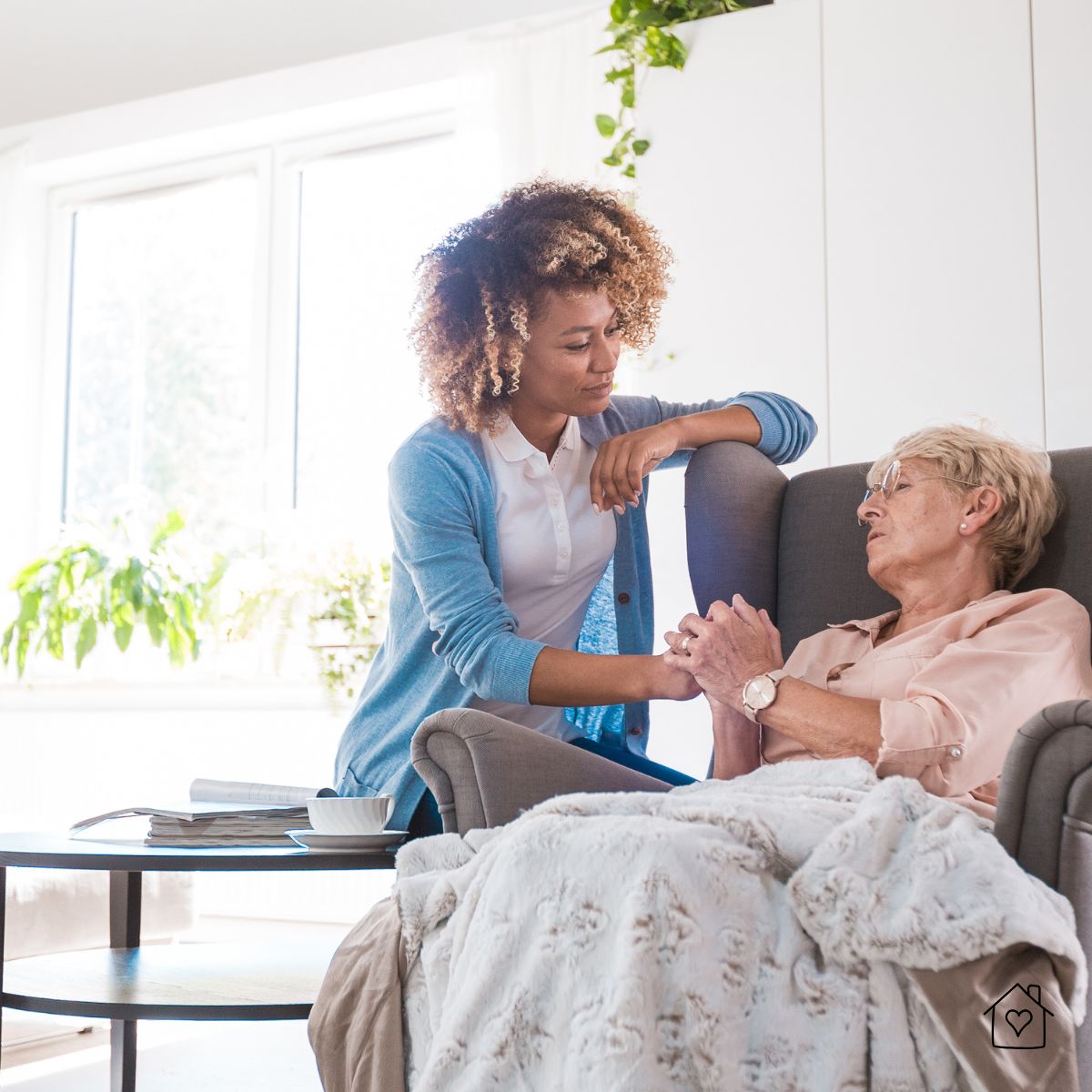 Caregiver holding hands with an older woman in a cozy home environment, demonstrating emotional support and comfort for senior residents.