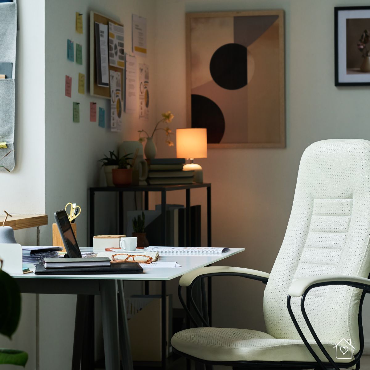 Padded ergonomic chair at a tidy desk with a warm table lamp creating focused, comfortable lighting.
