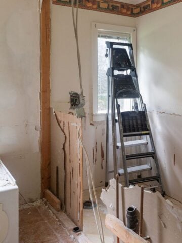 Bathroom remodel in Milwaukee mid-demolition, with exposed walls, pipes, and a ladder near the bathtub as part of renovation work.