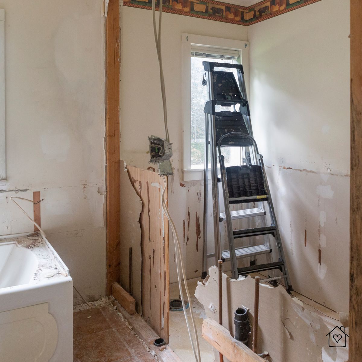 Bathroom remodel in Milwaukee mid-demolition, with exposed walls, pipes, and a ladder near the bathtub as part of renovation work.