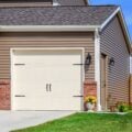 Brown vinyl-sided New Jersey home with white garage door and brick accents on a sunny day