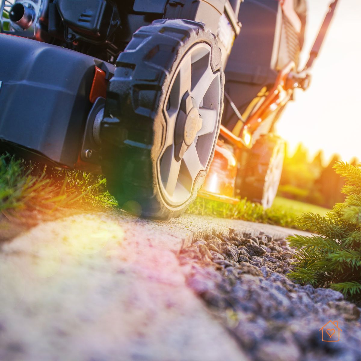 Close-up of lawn mower wheel cutting along an edge at sunset.