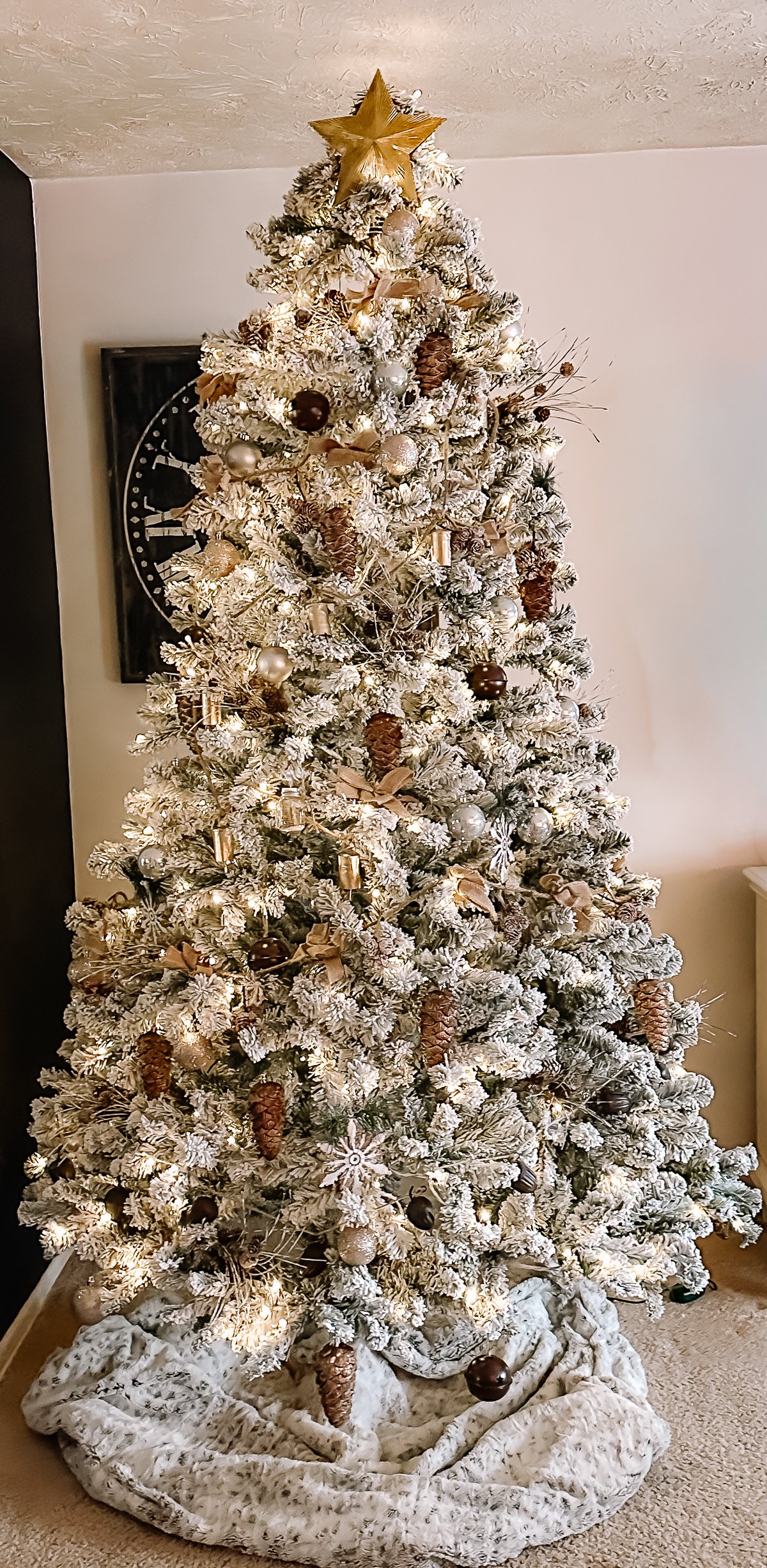 Flocked 8-foot tree with bronze and champagne ornaments, pinecones, burlap bows, warm lights.