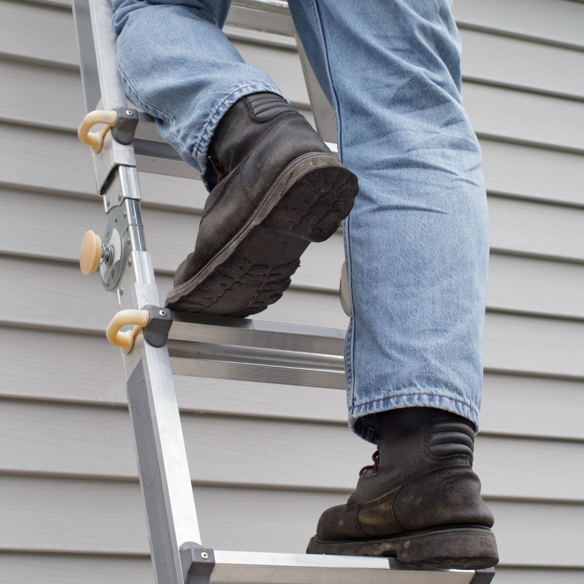 Close-up of non-slip boots standing squarely on ladder rungs with body centered between the side rails.