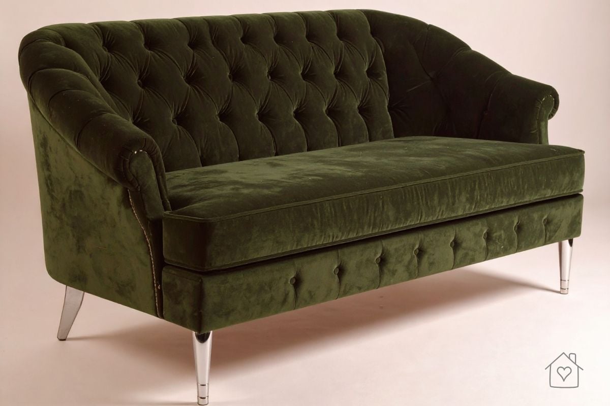 Deep-green tufted velvet loveseat with slim metal legs; compact curved back adds a soft focal point for a small living room.