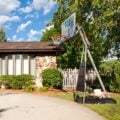 Portable basketball hoop on suburban driveway under blue sky