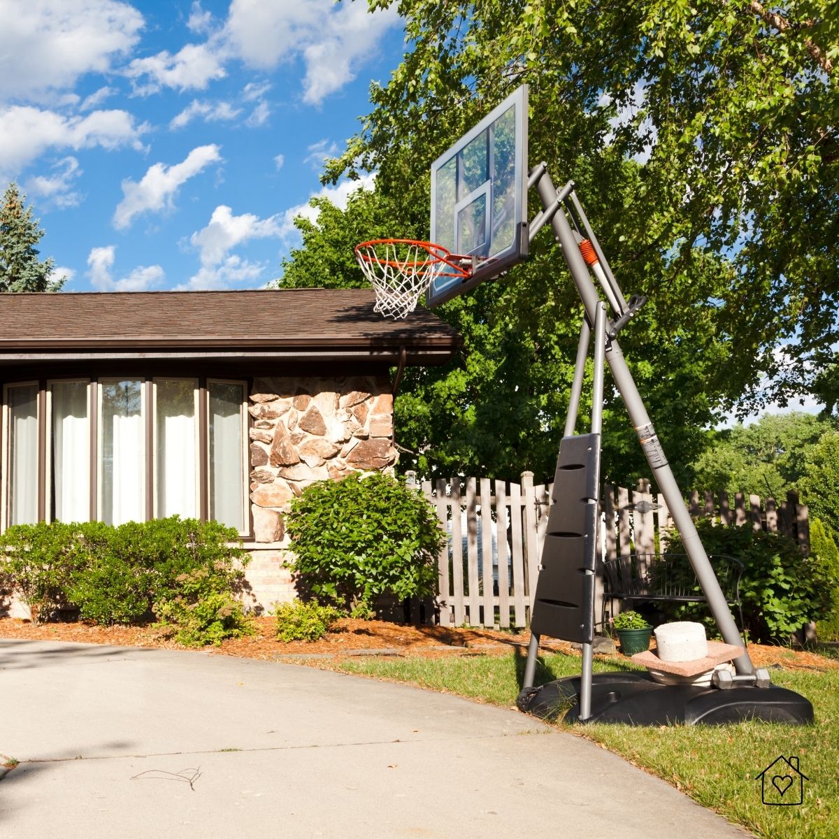 Portable basketball hoop on suburban driveway under blue sky