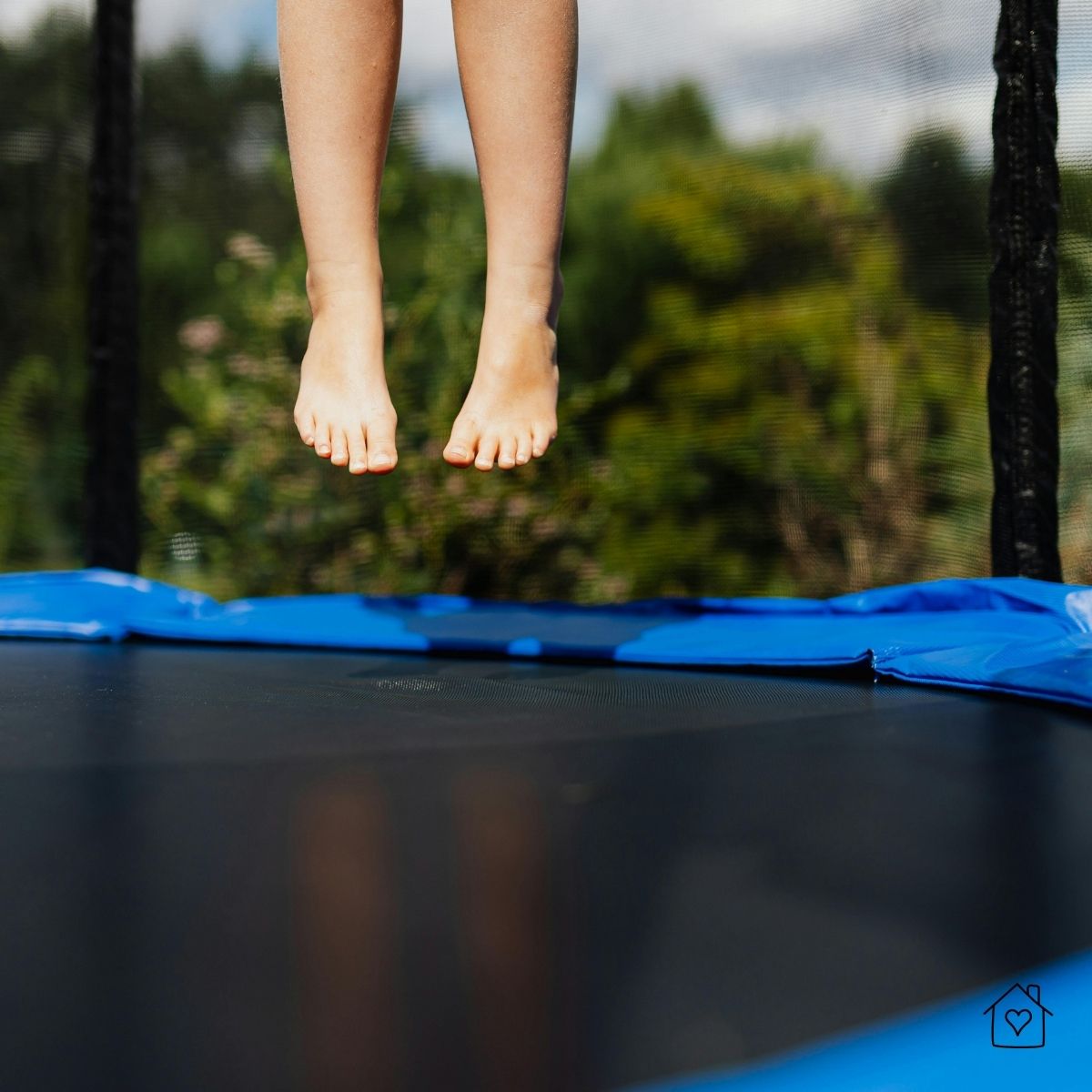 Child’s feet bouncing on trampoline with safety netting