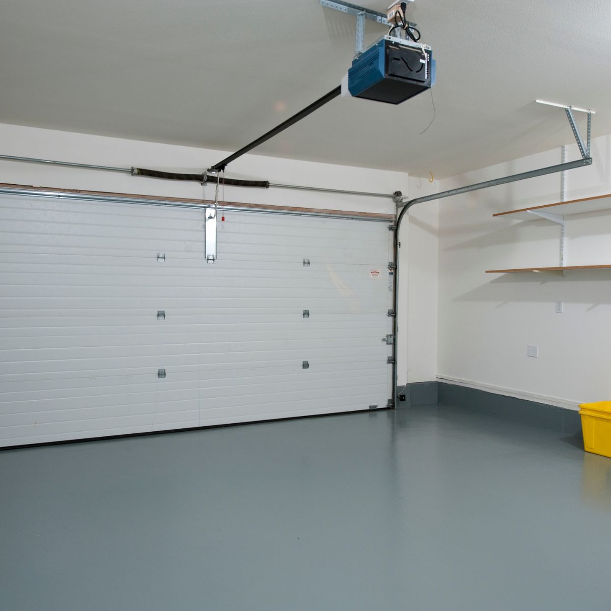 Interior view of a garage door with opener, track, and torsion spring assembly