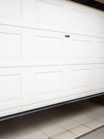 White garage door stuck half-open at the threshold—common sign your system needs inspection or repair