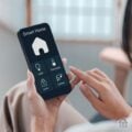 Close-up of a woman using a smartphone smart home app to manage lights, thermostat, locks, and security cameras.