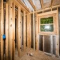 Interior of a home stripped to studs during a zero-cycle renovation, exposing framing, insulation, and window placement.