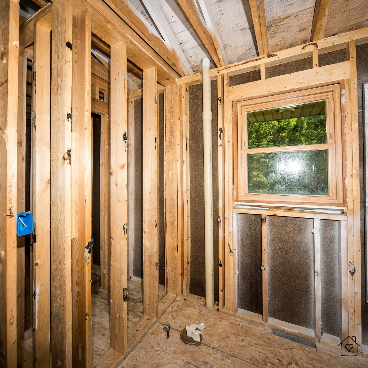 Interior of a home stripped to studs during a zero-cycle renovation, exposing framing, insulation, and window placement.